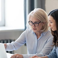 Image of women talking and looking at laptop