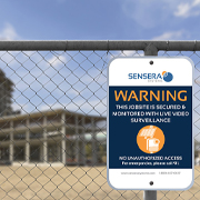 Surveillance warning sign on a fence outside a jobsite