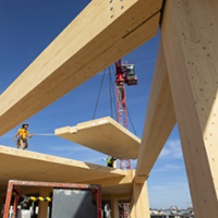 View from ground as mass timber being lowered onto a building